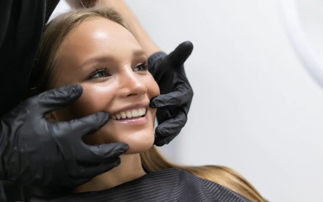 Smiling girl looks in mirror while cosmetic dentist points to her teeth.