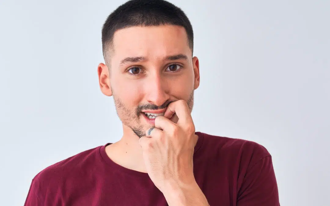 Man thinking with hand near mouth, considers veneers for crooked teeth