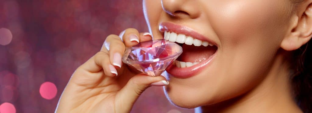 Happy woman bites down on large diamond with beautiful, strong white teeth